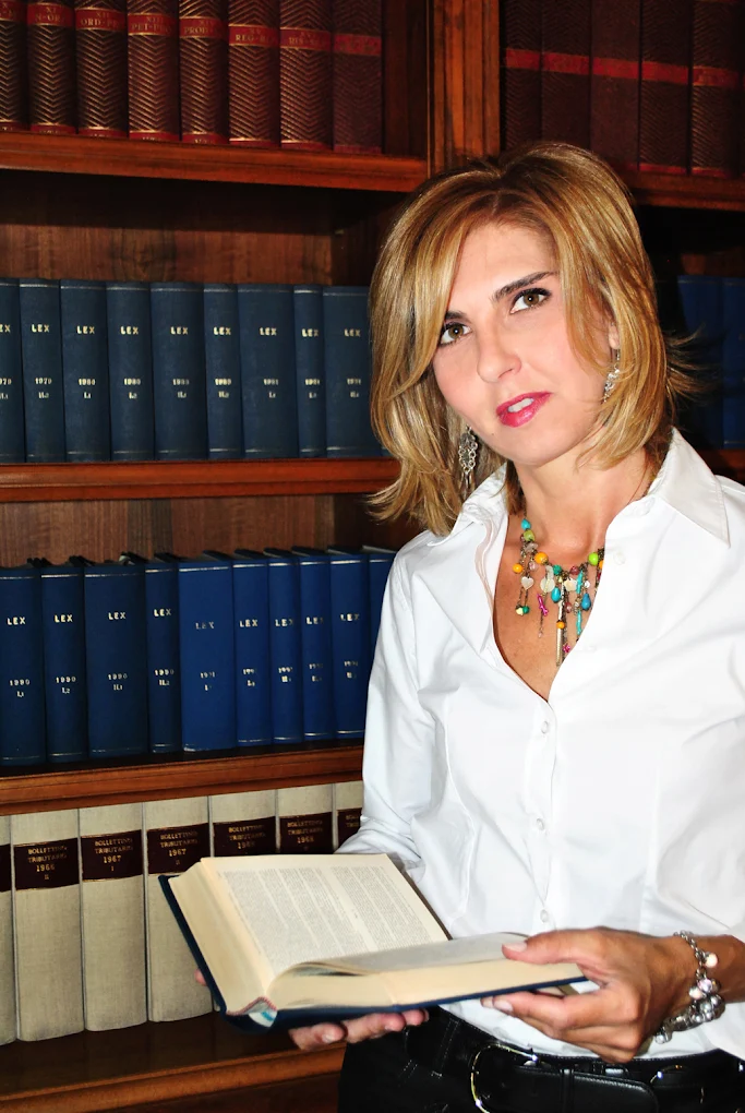 Ritratto dell'Avvocato Claudia Pacini con libri di legge e codici in biblioteca.